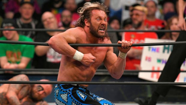 Kenny Omega clings to the ring ropes during a match